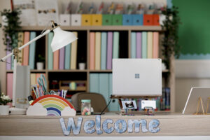 A teachers desk with a welcome sign and colourful books and laptop