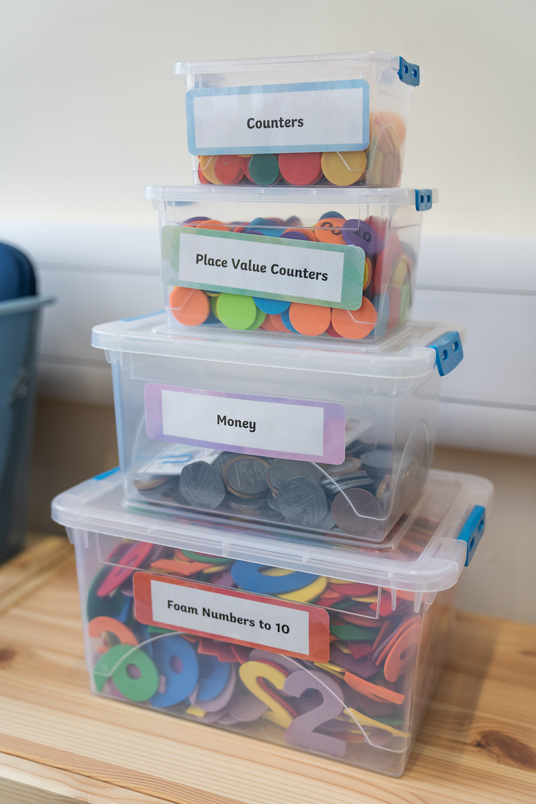 a stack of plastic boxes containing counters and numbers to be used for maths practise