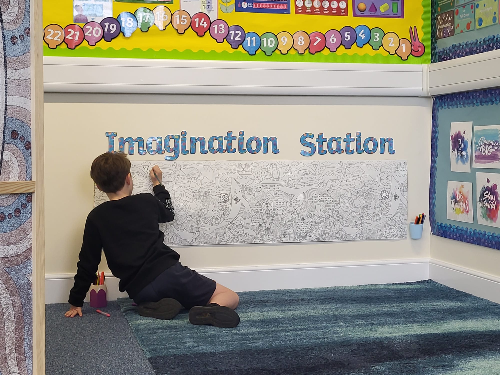 a child playing with the imagination wall on his own