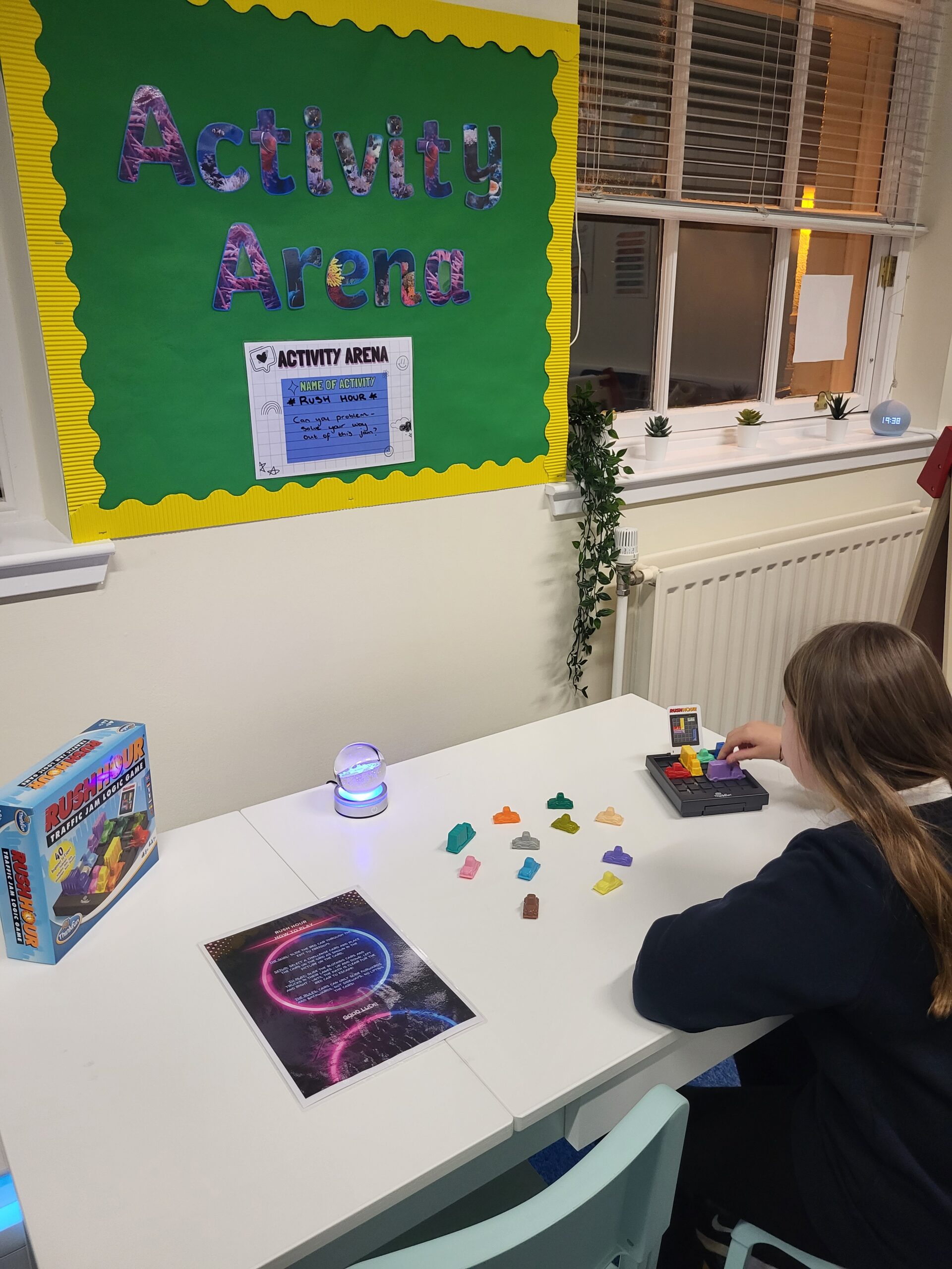 a picture of a girl playing the game rush hour on a white table in a classroom