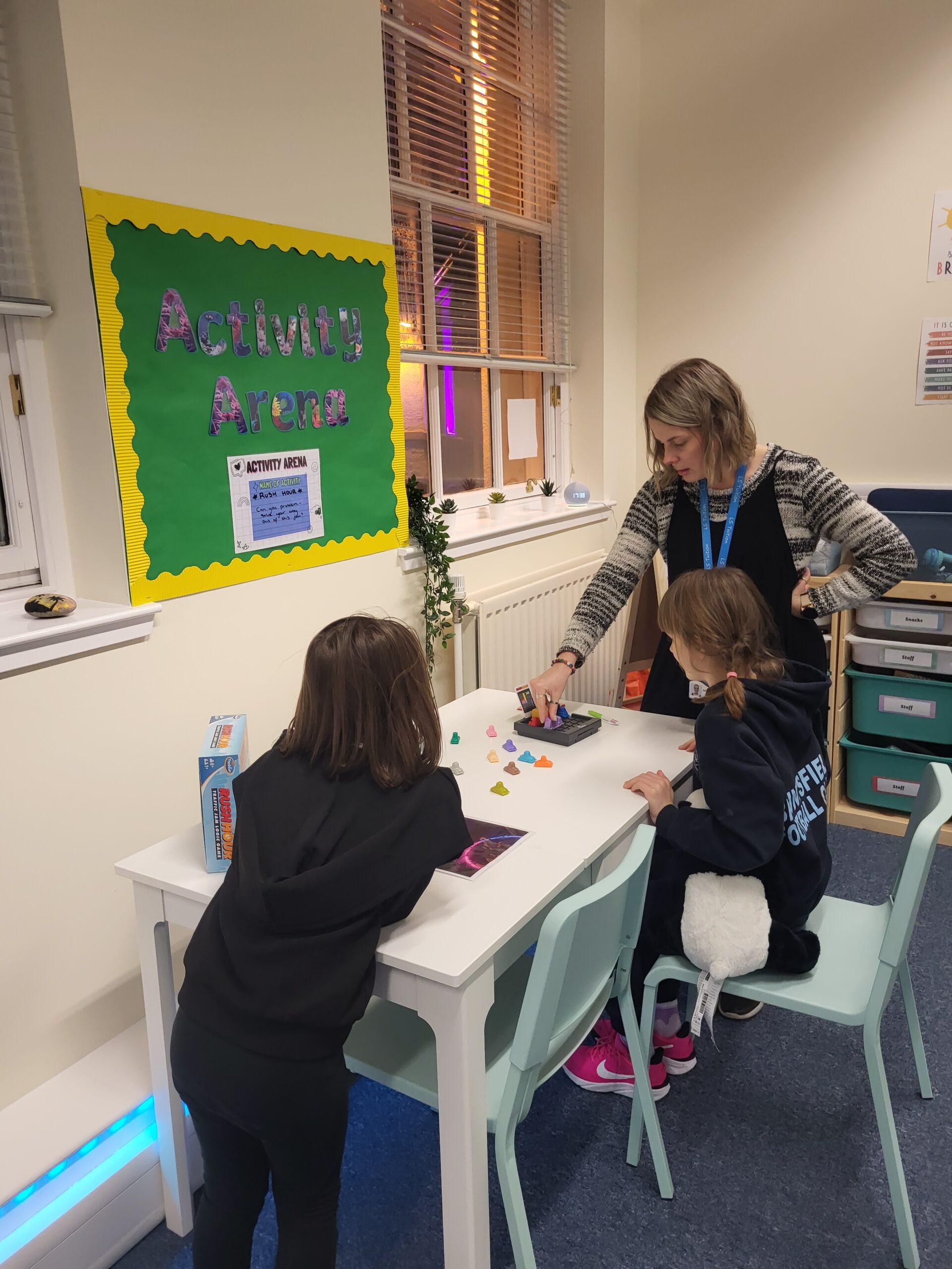 a picture of a teacher and two girls playing the game rush hour in a classroom