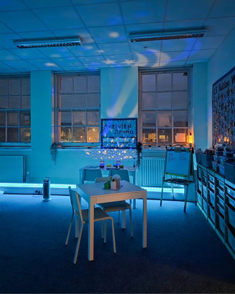 An image of the Learning Space light up at night time with stars projected on the walls