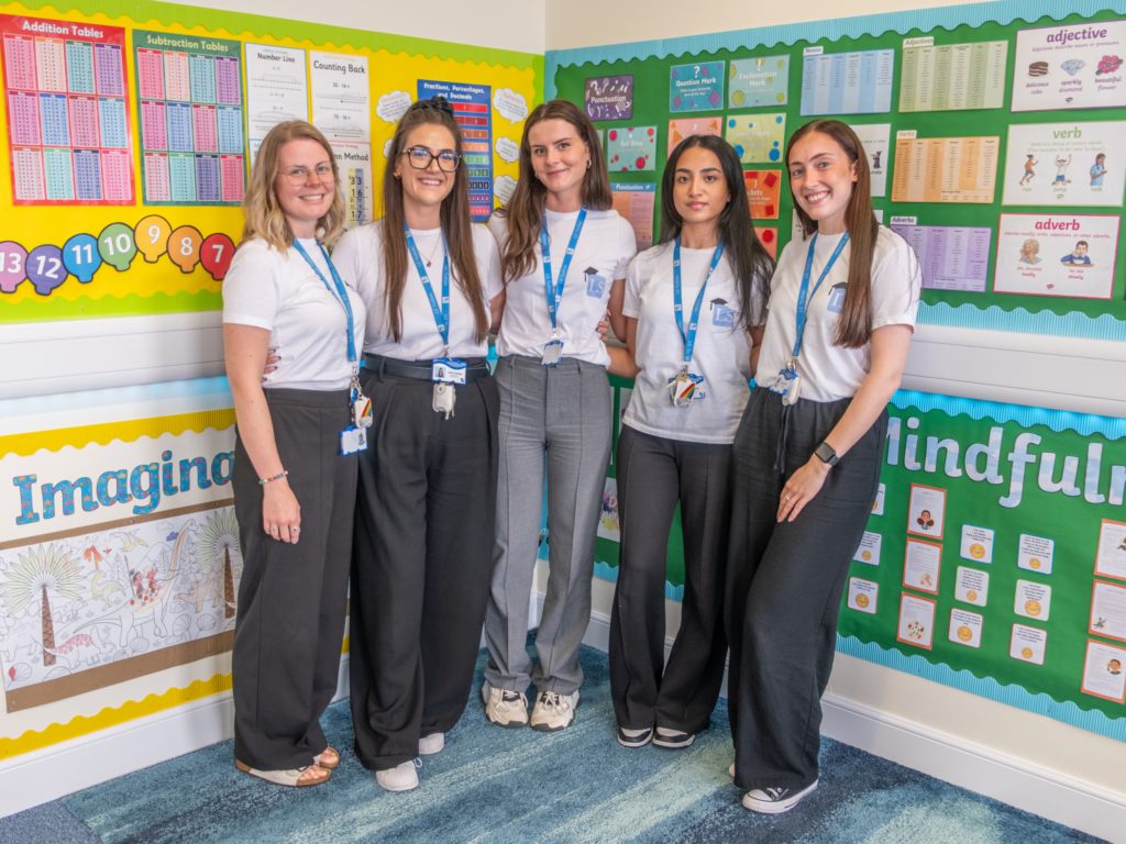 meet the team of 5 LS Tuition Tutors stand together in the classroom, smiling and happy in their LS Tuition Holiday Clubs T-shirts