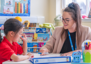 Lydia and a student sit at a desk in the LS Tuition Learning Space
